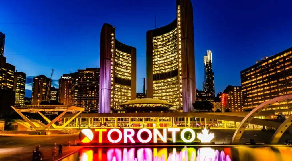 Toronto skyline with CN Tower and Rogers Centre, geese swimming in the foreground under a clear blue sky, ideal for studying in Canada