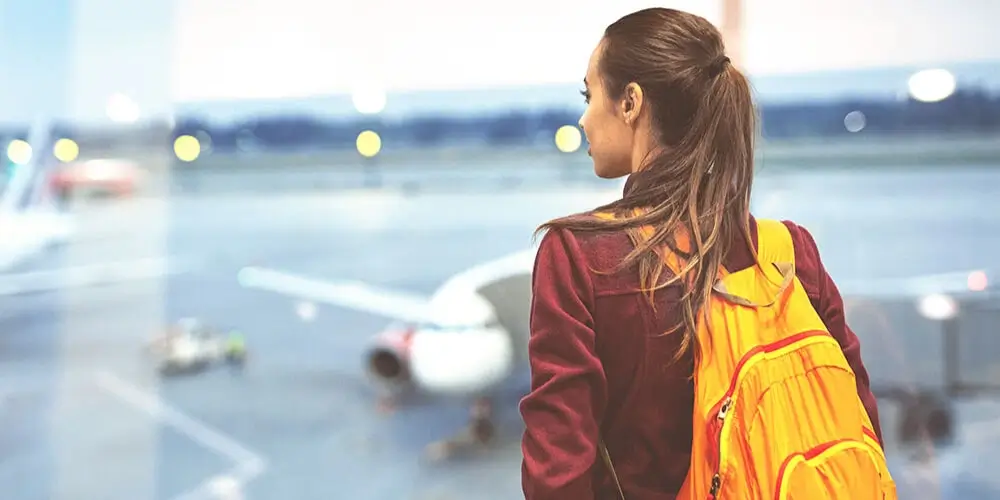 Female student at the airport with backpack receiving pre-departure guidance for studying abroad