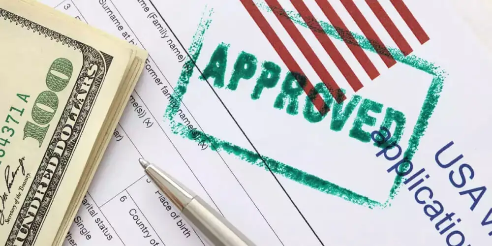 Approved USA visa application form with pen and US dollar bills, representing successful visa consultancy services for study abroad